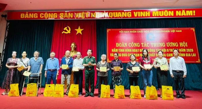 Trung tướng Nguyễn Hữu Chính - Chủ tịch Trung ương Hội Nạn nhân chất độc da cam/dioxin Việt Nam (thứ 7 từ trái qua) tặng quà cho các nạn nhân chất độc da cam phường Quy Nhơn. Ảnh: Phan Tuấn