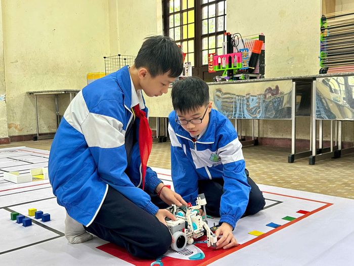 2 em Nhật và Khôi trao đổi, điều chỉnh robot trong quá trình thử nghiệm