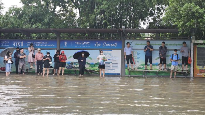 Học sinh gặp khó khăn khi di chuyển tại khu vực xe buýt đưa đón sau mưa lớn.