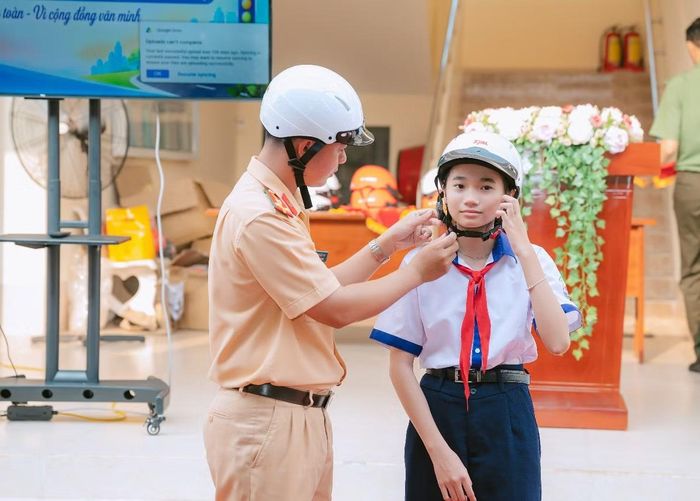 Cán bộ Phòng Cảnh sát giao thông hướng dẫn cách đội mũ bảo hiểm an toàn cho các em học sinh.