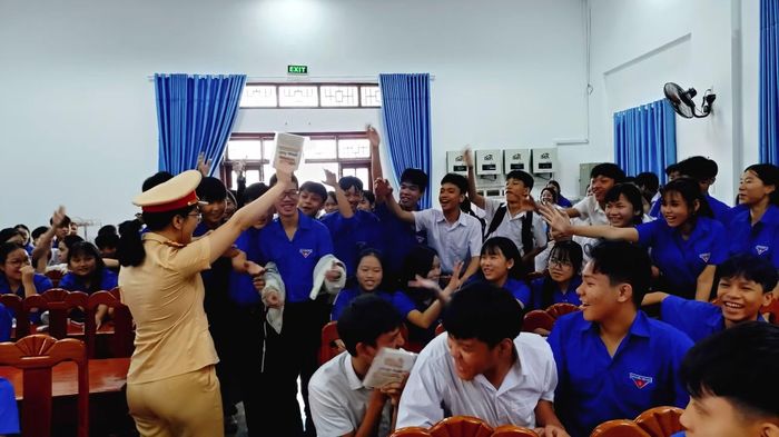 Cán bộ CSGT phát sổ tay an toàn giao thông cho các em học sinh.