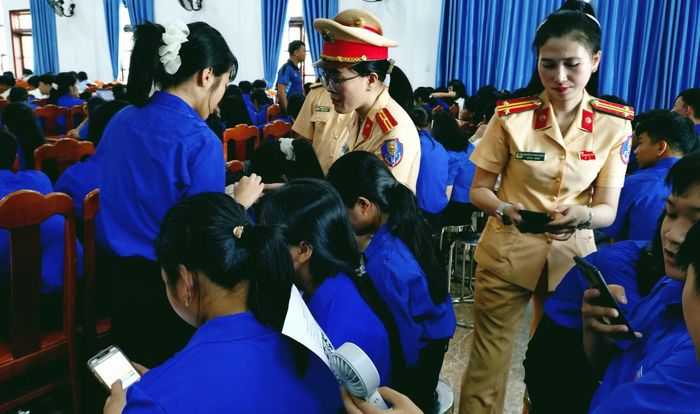 Cán bộ CSGT hướng dẫn các em học sinh quét mã QR để vào ứng dụng thi tìm hiểu, đánh giá nhận thức pháp luật về TTATGT.