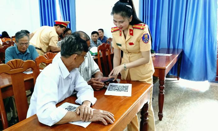 Cán bộ CSGT hướng dẫn người dân quét mã QR để vào ứng dụng thi tìm hiểu, đánh giá nhận thức pháp luật về TTATGT.
