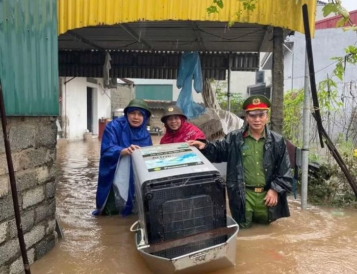 Công an xã Dân Hòa giúp người dân di chuyển tài sản trong vùng ngập úng.