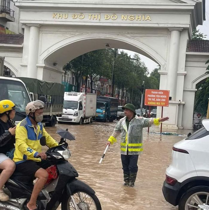 Công an phường Yên Nghĩa phân luồng giao thông cho các phương tiện tránh điểm ngập úng.