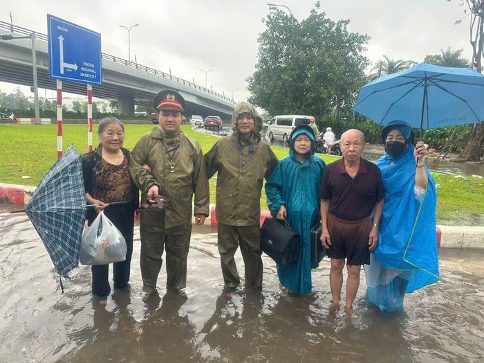 Cán bộ, chiến sĩ Công an phường Tây Mỗ kịp thời hỗ trợ nhân dân di chuyển an toàn qua khu vực ngập úng.
