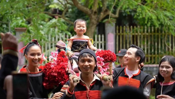 Bé Harley được 2 người thân kiệu vào sảnh tiệc.