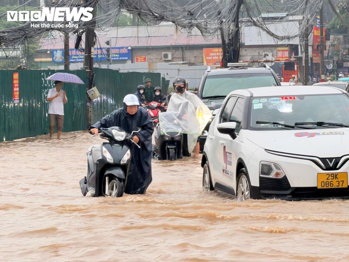 Người dân phải dò dẫm dắt xe máy qua khu vực ngập. (Ảnh: Minh Đức)