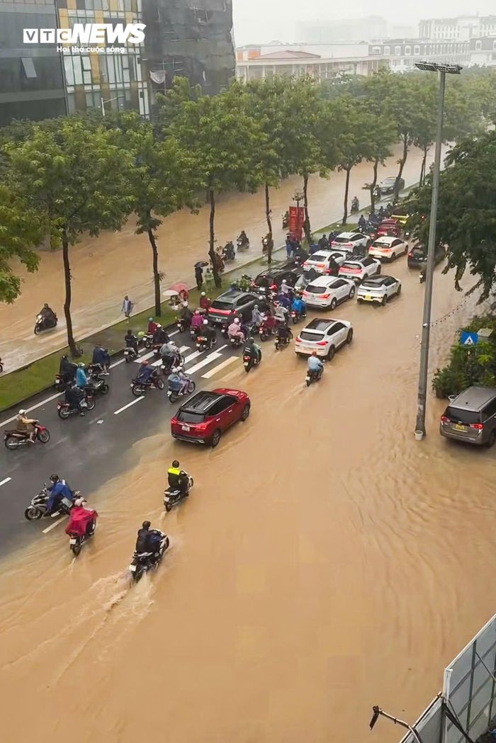Tại phố Trịnh Văn Bô (phường Xuân Phương), cả hai chiều đường đều phủ kín nước. Nhiều đoạn ngập sâu khiến ô tô, xe máy phải dò dẫm di chuyển. (Ảnh: Minh Quang)