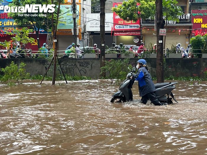 Người phụ nữ phải xuống xe dắt bộ qua khu vực ngập sâu. (Ảnh: Minh Đức)