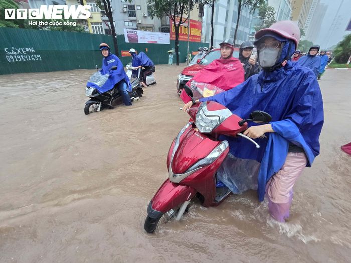 “Đường ngập sâu quá, xe máy không thể đi qua nên tôi đành quay lại tìm đường khác. Sáng nay chắc phải chấp nhận đi làm muộn”, nữ tài xế nói. (Ảnh: Đắc Huy)