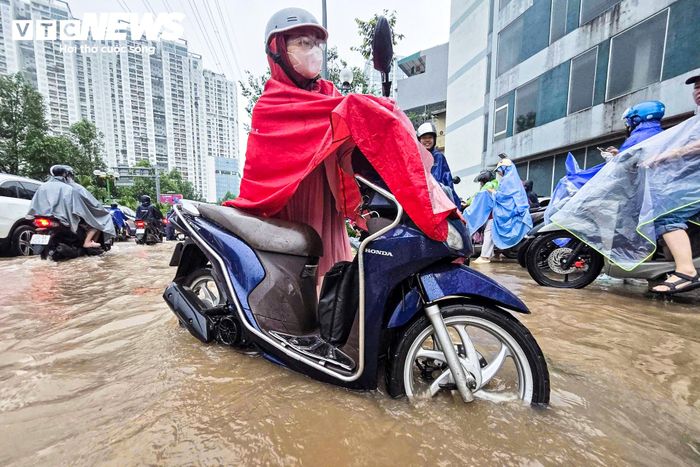 Không thể tiếp tục chạy xe, nhiều người xuống dắt bộ, men theo dải phân cách để tìm cách vượt qua đoạn ngập. 