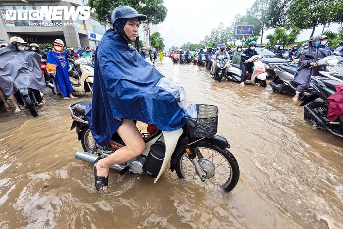 Mỗi khi ô tô hoặc xe tải chạy qua, nước bị dồn thành từng đợt, khiến người đang dắt xe phải chật vật giữ thăng bằng.