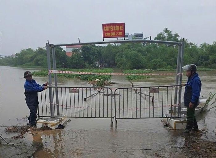 Lực lượng chức năng xã Quảng Bị túc trực cấm người và phương tiện qua cầu bắc qua sông Đáy. Ảnh: Phương Liên