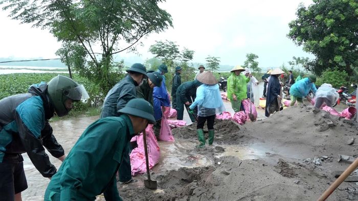 Các lực lượng chức năng và nhân dân xã Mỹ Đức đắp đê bao cát ngăn nước tràn. Ảnh: Biên Phạm