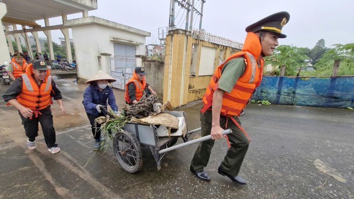 Các chiến sĩ Cảnh sát cơ động phối hợp với Xí nghiệp thủy lợi Gia Lâm, lực lượng chức năng xã Phù Đổng dọn rác, khơi thông dòng chảy khu vực trạm bơm Phù Đổng. Ảnh: Văn Ba