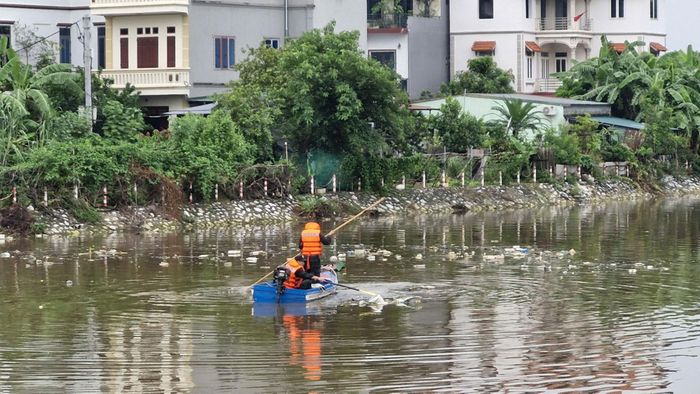 Các chiến sĩ Cảnh sát cơ động phối hợp với Xí nghiệp thủy lợi Gia Lâm, lực lượng chức năng xã Phù Đổng dọn rác, khơi thông dòng chảy khu vực trạm bơm Phù Đổng. Ảnh: Văn Ba