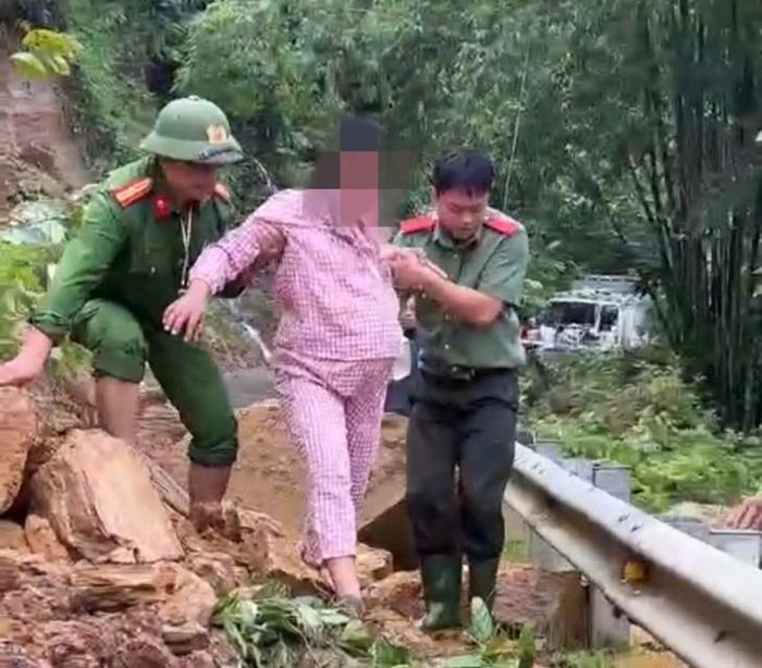 Công an hỗ trợ đưa chị T. qua điểm đường bị chia cắt, nhanh chóng đến cơ sở y tế gần nhất. Ảnh: CATH.