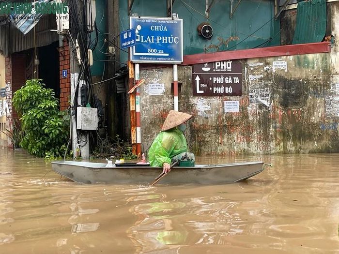 Một số người dân phải sử dụng thuyền để di chuyển trên phố. Người dân mặc áo mưa, ngồi trên chiếc thuyền nhỏ và dùng mái chèo di chuyển giữa dòng nước, để vận chuyển thức ăn và nhu yếu phẩm. Ảnh: Phúc Đức