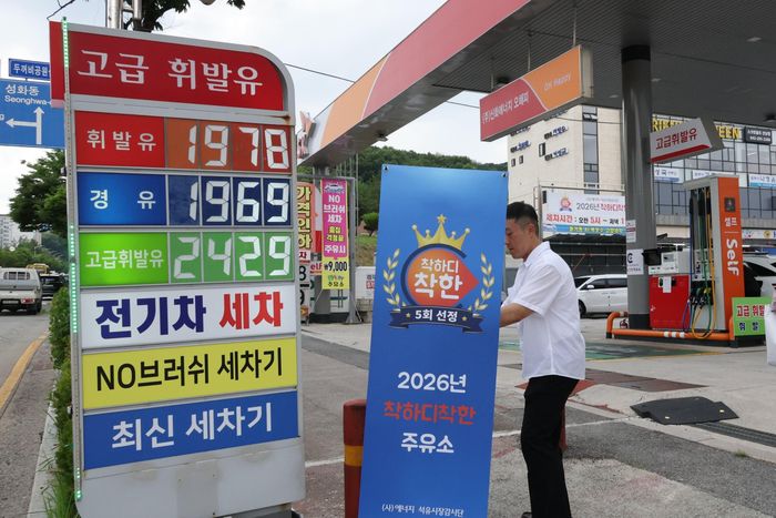 Một nhân viên dựng biển chứng nhận tại trạm xăng Ohappy ở Cheongju, tỉnh Bắc Chungcheong, Hàn Quốc, ngày 2/9. Trạm này được công nhận là “trạm xăng tốt” 5 lần kể từ khi chính sách giá trần xăng dầu được áp dụng ngày 13/3. Ảnh: Yonhap.