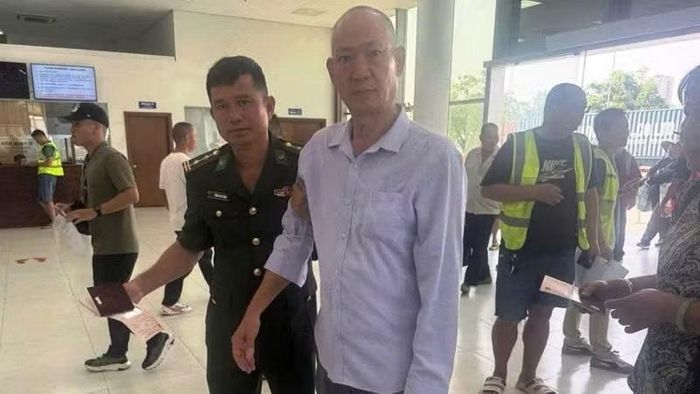Cán bộ Đồn Đồn Biên phòng cửa khẩu quốc tế Móng Cái hỗ trợ đưa nam hành khách người Trung Quốc làm thủ tục xuất cảnh. (Ảnh: Quang Thọ)