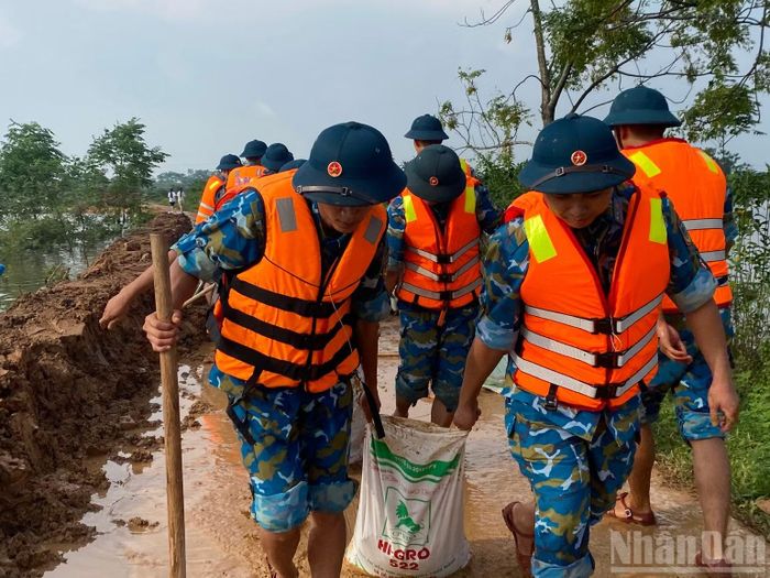 Chiến sĩ dùng bao tải đất gia cố đê. (Ảnh: QUANG PHONG)