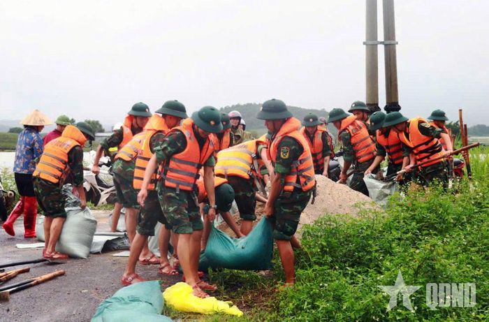 Cán bộ, chiến sĩ Quân đoàn 12 phối hợp với lực lượng địa phương và nhân dân khẩn trương gia cố tuyến đê, ngăn nước lũ tràn vào khu dân cư. 