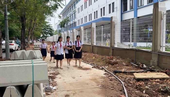  Bó vỉa bê tông, đất đá, vật liệu vương vãi gây mất an toàn nơi cổng trường. ẢNh: XUÂN QUỲNH 