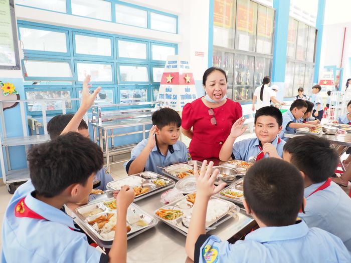  Nhân viên y tế Trường Tiểu học Lê Thị Riêng (phường Hòa Hưng, TPHCM) lắng nghe ý kiến học sinh tại bữa ăn bán trú ngày 15-9 