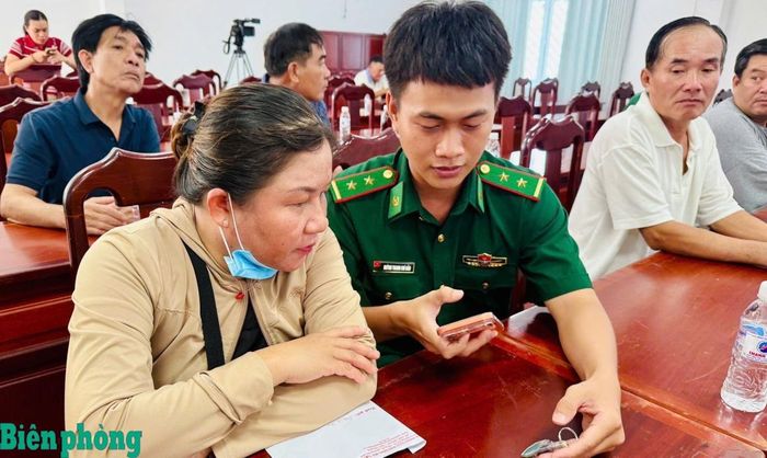 Cán bộ Đồn Biên phòng cửa khẩu quốc tế Hà Tiên hướng dẫn người dân sử dụng điện thoại thông minh quét mã QR trên móc khóa. Ảnh: Thu Ngân