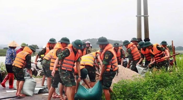 Cán bộ, chiến sĩ Quân đoàn 12 phối hợp với lực lượng địa phương và nhân dân khẩn trương gia cố tuyến đê, ngăn nước lũ tràn vào khu dân cư (ảnh: Khánh Trình).