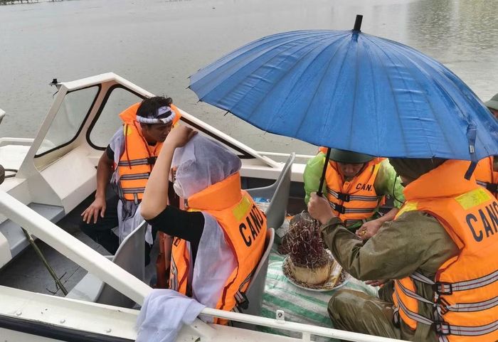 Lực lượng cảnh sát dùng xuồng máy hỗ trợ người dân đưa hài cốt người thân vượt vùng lũ về nhà.