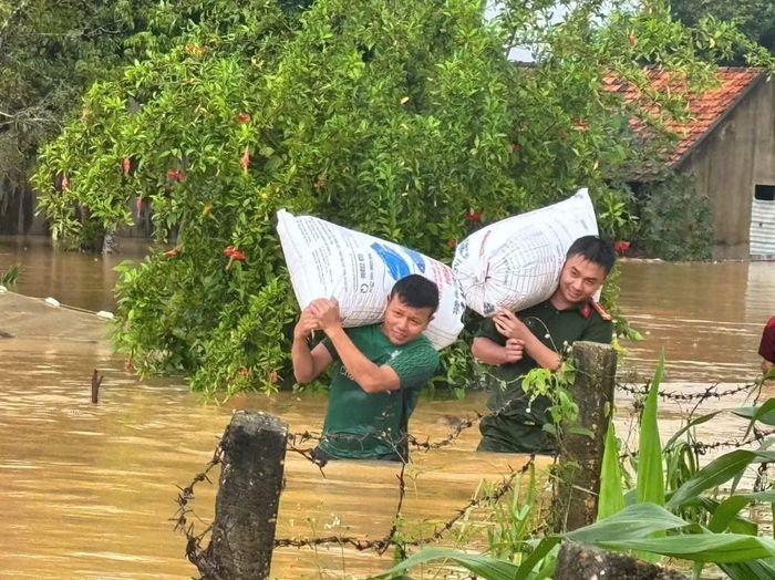 Công an, lực lượng quân sự xã Nghĩa Lộc hỗ trợ vận chuyển lúa, tài sản ra khỏi nhà ngập lụt.