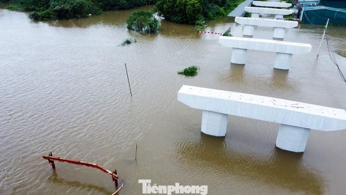 Nước lũ sông Đáy dâng ngập khiến cây cầu cũ hoàn toàn mất dấu, mực nước dâng cao chạm gần đến đỉnh hai trụ cọc ở đầu cầu. (Đồ hoạ minh hoạ vị trí cầu 72 - ảnh bên trái)