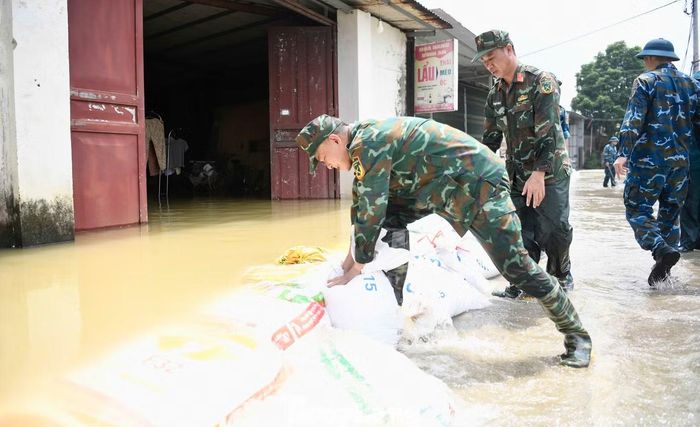 Trưa 18/9, lực lượng chức năng xã Quảng Bị dùng đất, cát đắp bờ ngăn nước tràn vào khu dân cư để bảo vệ tài sản của người dân.
