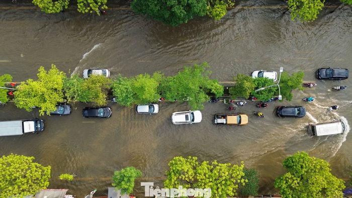Các phương tiện nối nhau đi qua đoạn ngập, nhiều ôtô con phải di chuyển chậm khi nước dâng cao gần bánh xe.