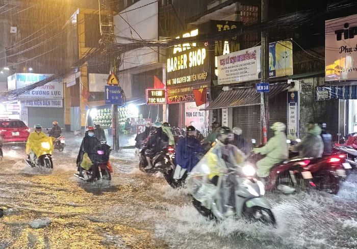 Đoạn đường gần cổng Đình Phong Phú ngập sâu gần lút bánh xe máy khiến việc đi lại hết sức khó khăn, nhiều người chọn cách tấp xe vào lề chờ bớt mưa và giảm ngập để có thể tiếp tục hành trình.