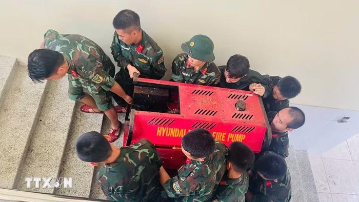 Bộ đội hỗ trợ di dời tài sản của Trường Mầm non Xuân Mai (xã Xuân Mai, Hà Nội) lên cao. (Ảnh: TTXVN phát)