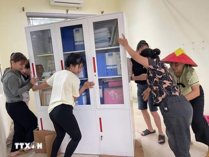 Người dân hỗ trợ di dời tài sản của trường Mầm non Xuân Mai (xã Xuân Mai, Hà Nội) lên cao tránh nước ngập. (Ảnh: TTXVN phát)