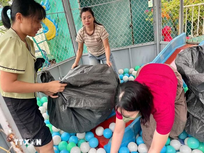Giáo viên trường Mầm non Xuân Mai (xã Xuân Mai, Hà Nội) thu dọn đồ chơi, tránh nước ngập. (Ảnh: TTXVN phát)