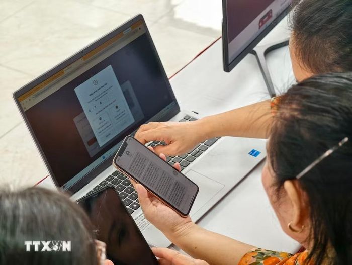 Thành viên Tổ chuyển đổi số cộng đồng hướng dẫn người dân tiếp cận, sử dụng các tiện ích số. (Ảnh: Trung Nguyên/TTXVN)