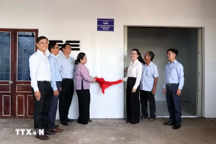 Lãnh đạo thành phố Cần Thơ và chính quyền địa phương thực hiện tháo khăn, gắn biển bàn giao nhà mới cho gia đình bà Võ Thị Liến. (Ảnh: Trung Kiên/TTXVN)