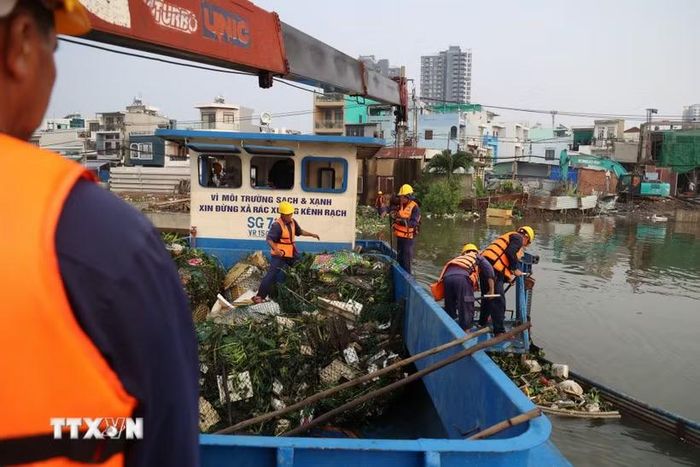 Công nhân Công ty Trách nhiệm hữu hạn Một thành viên Dịch vụ công ích Quận 8 vớt rác trên kênh Đôi, đoạn qua phường Phú Định. (Ảnh: Hồng Đạt/TTXVN)