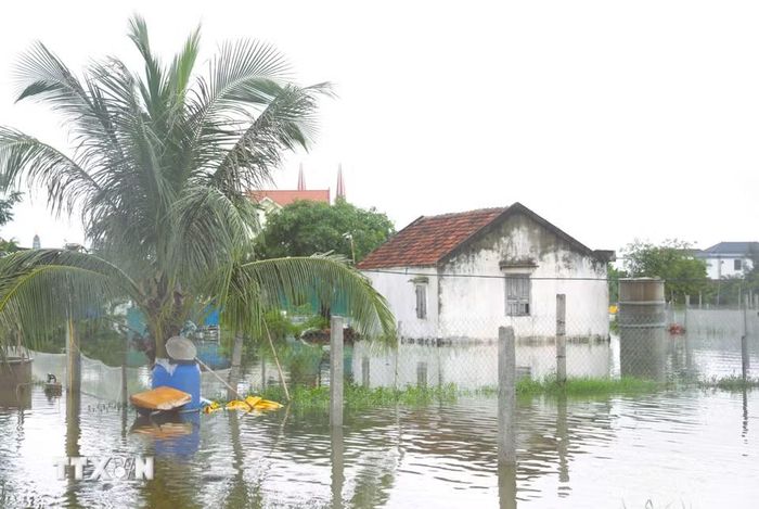 Nước bủa vây, gây ngập nặng và tạm thời cô lập nhà dân. (Ảnh: Xuân Tiến/TTXVN)