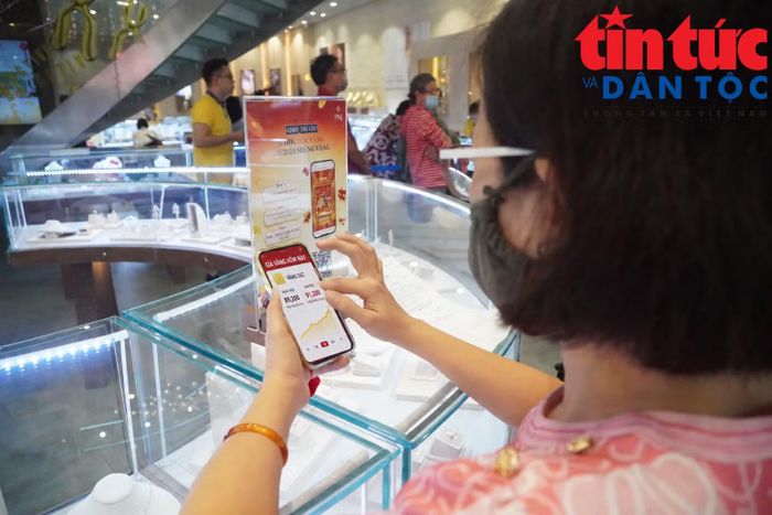 Khách hàng theo dõi diễn biến giá vàng trên điện thoại trước khi quyết định giao dịch.