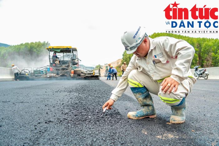 Công nhân kiểm tra độ giãn nở của mặt đường sau khi trải nhựa.