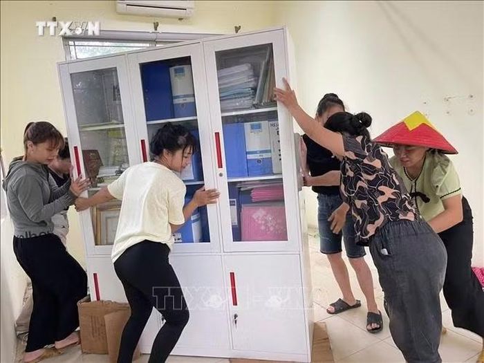 Người dân hỗ trợ di dời tài sản của trường Mầm non Xuân Mai (xã Xuân Mai, Hà Nội) lên cao tránh nước ngập. Ảnh: TTXVN phát