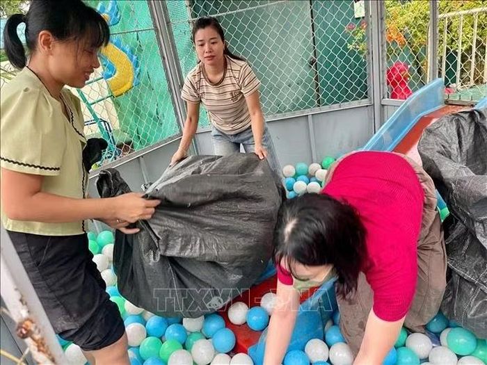Giáo viên trường Mầm non Xuân Mai (xã Xuân Mai, Hà Nội) thu dọn đồ chơi, tránh nước ngập. Ảnh: TTXVN phát.
