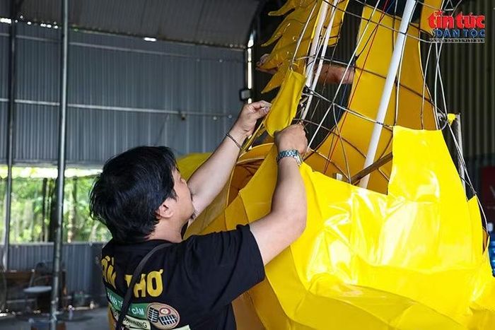 Từng lớp vật liệu màu được cắt, dán thủ công theo đường nét của khung thép để tạo hình cho tác phẩm.