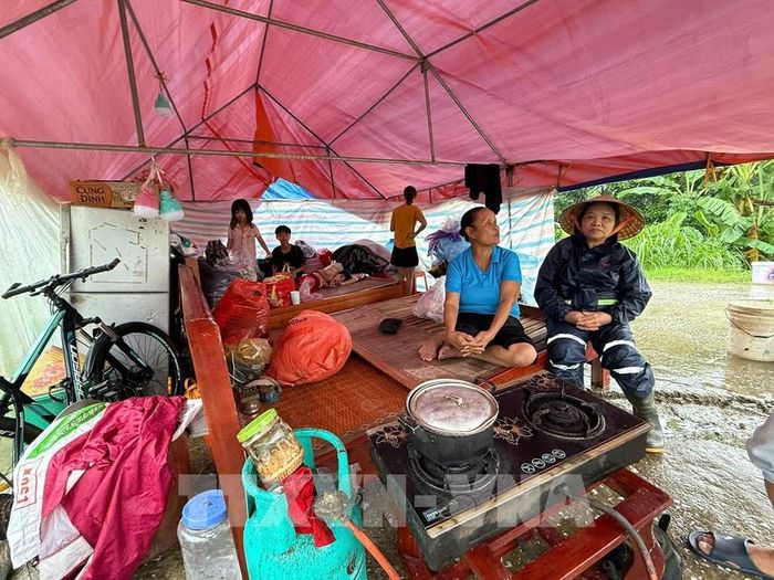 Mưa, rét, khó khăn đủ bề nhưng gia đình bà Vũ Thị Chừ, 72 tuổi, xã Kim Tân vẫn động viên nhau cùng cố gắng, đợi nước rút sẽ về dọn dẹp nhà cửa. Ảnh: Hoa Mai - TTXVN